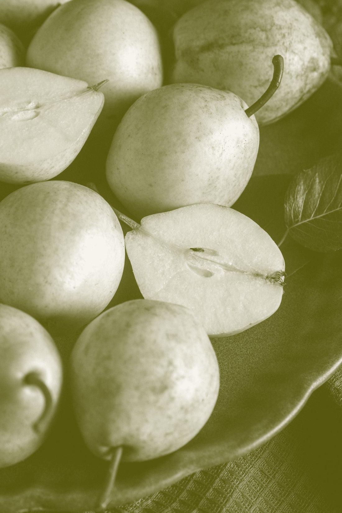 Round russeted nashi pears on a dark surface, one cut in half to show the pale flesh and core.